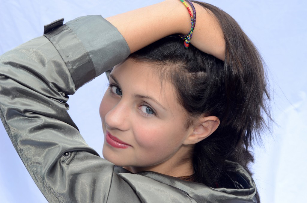 Portrait photography-young white female with her hand in her hair looks over her shoulder into the camera